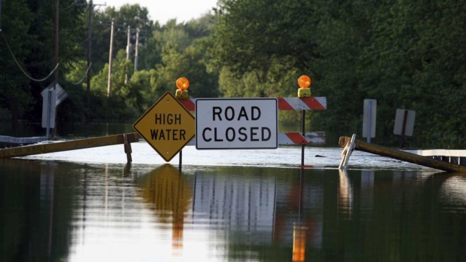 road closed signs and barricades blocking a flooded road