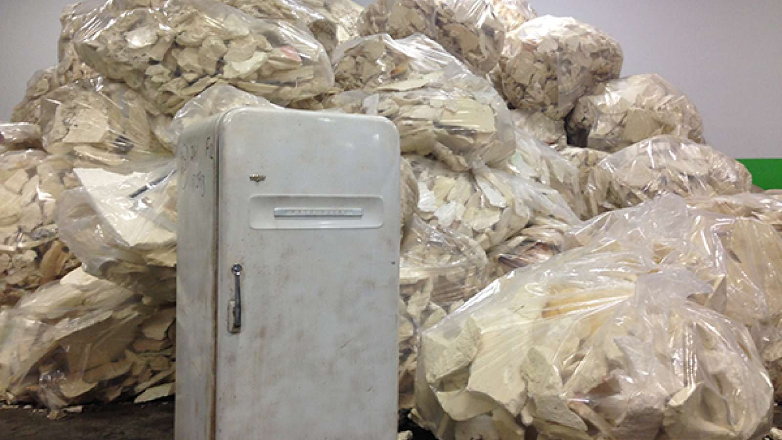 an old refrigerator in front of giant plastic bags of insulation foam
