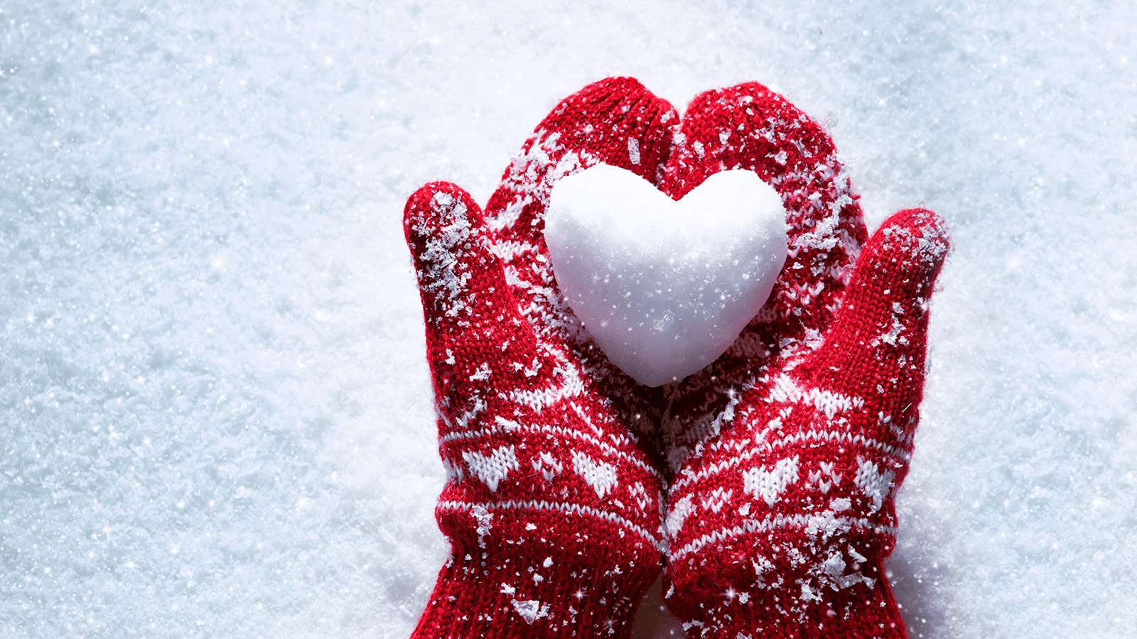 mittens holding a snowball in the shape of a heart