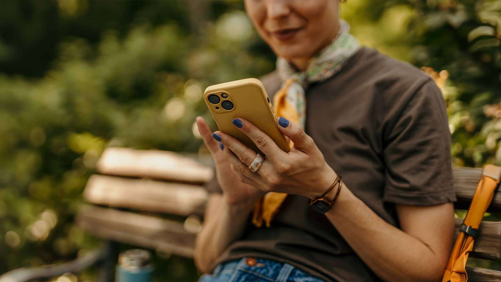 person sitting outside on a park bench looking at a mobile phone