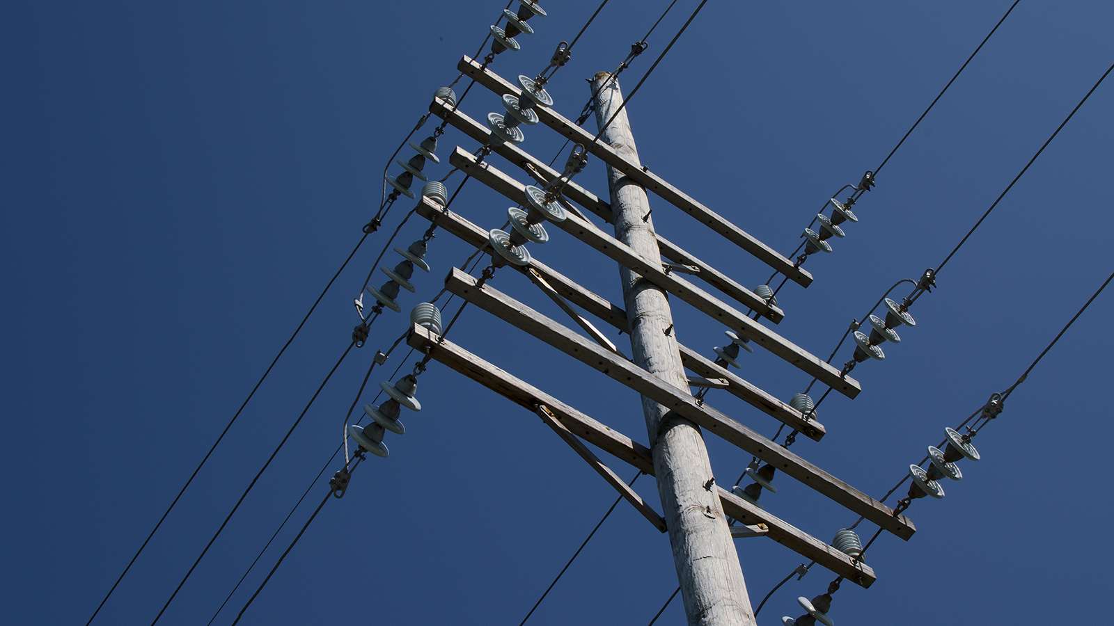 a power pole and power lines shot from the ground looking up.