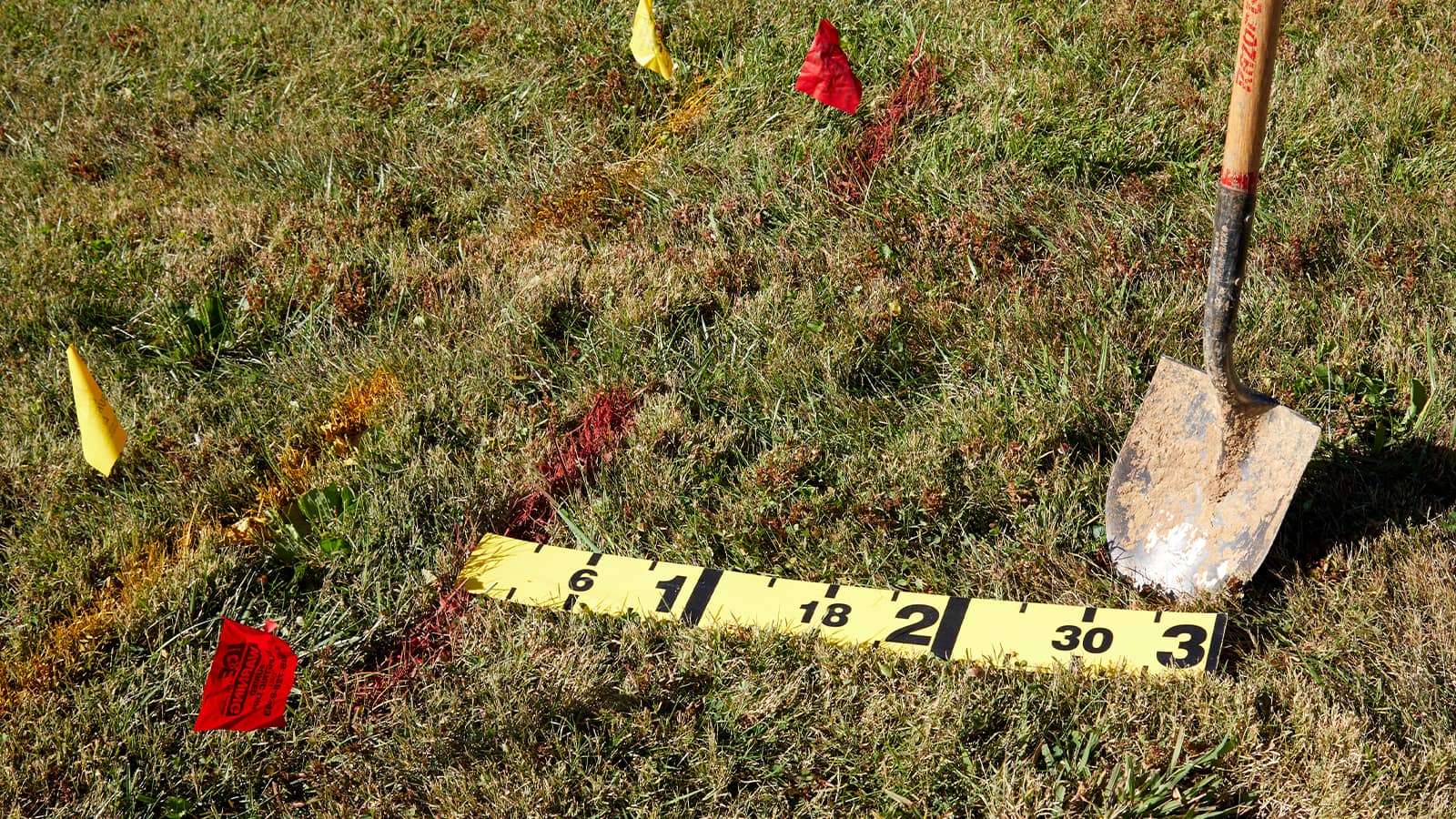 line marking flags and a shovel on a grass yard