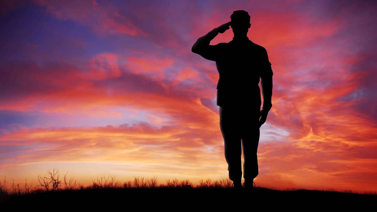 silhouette of a soldier saluting at sunset