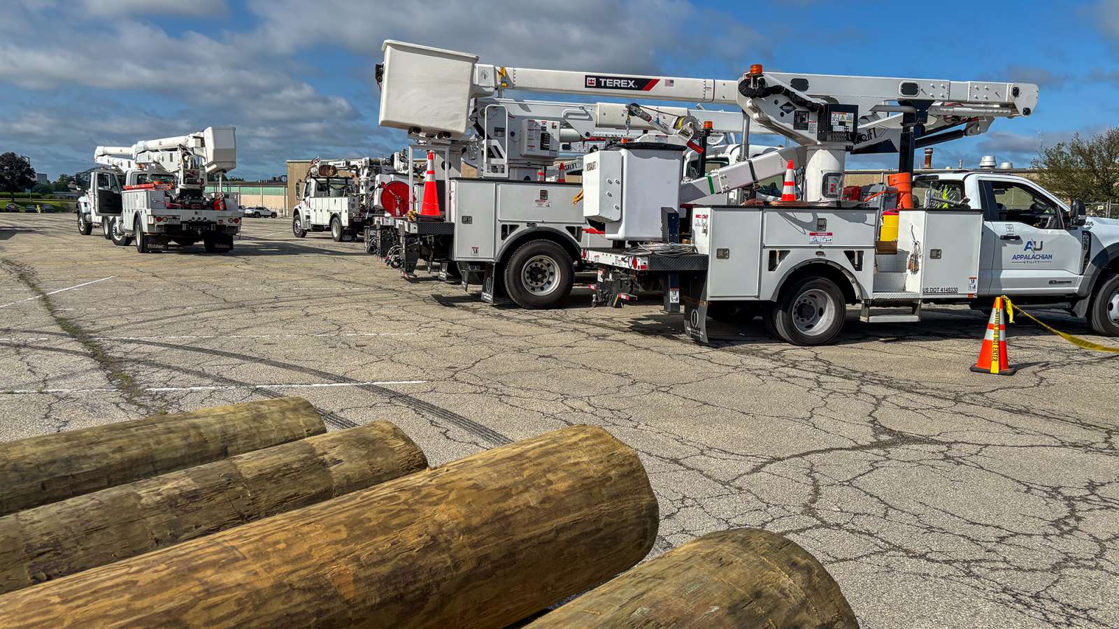bucket trucks staging with utility poles in the foreground