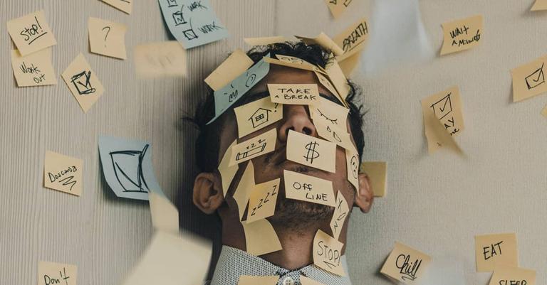 Man covered in sticky notes with financial symbols