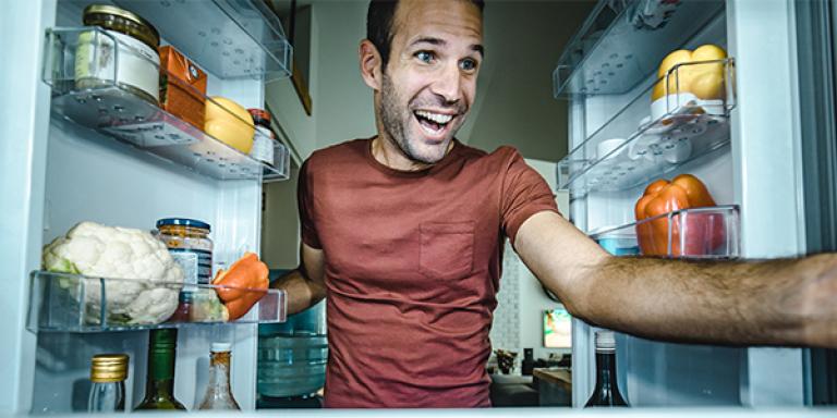happy man looking inside of a refrigerator