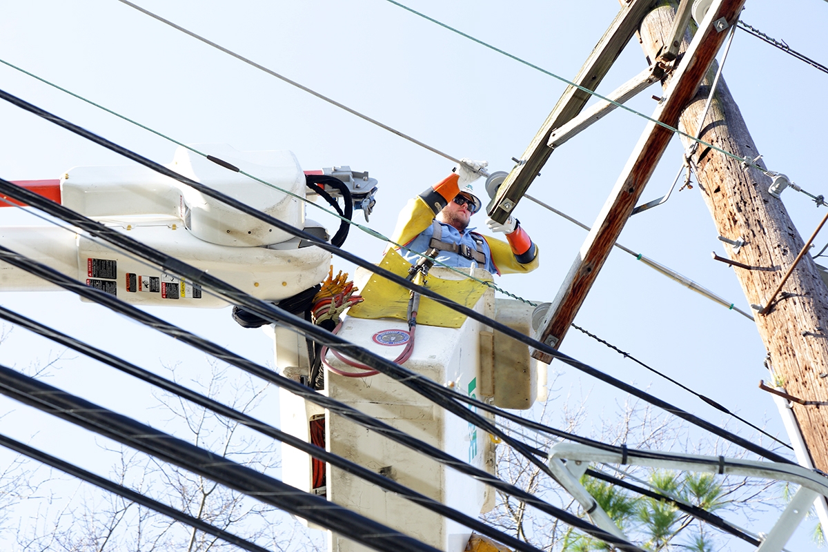 employee in bucket repairing power line on a pole