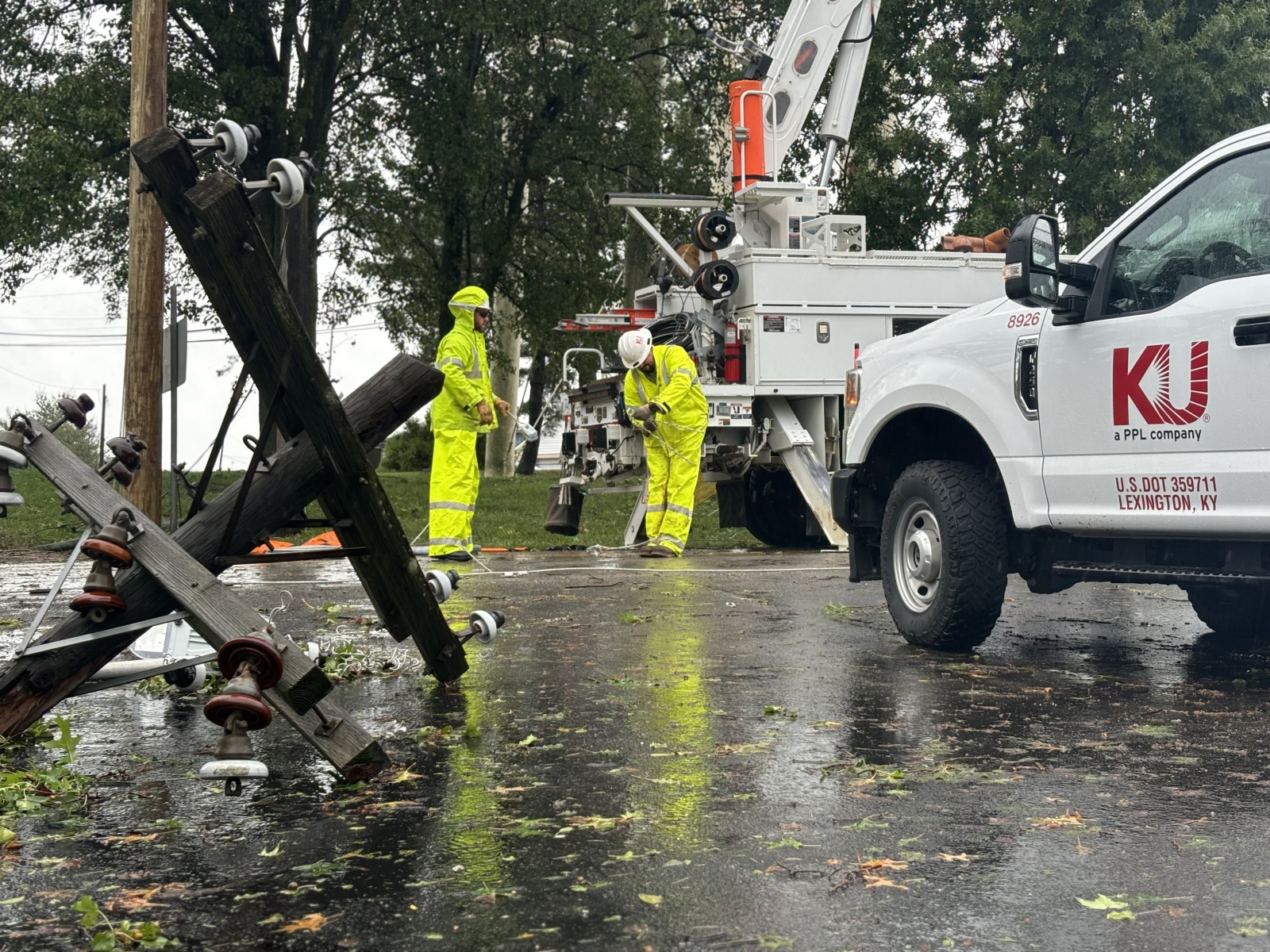 broken top to power pole with crew next to truck in background