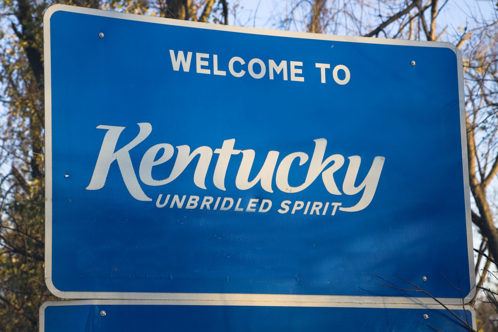 blue road sign that reads "Welcome to Kentucky"