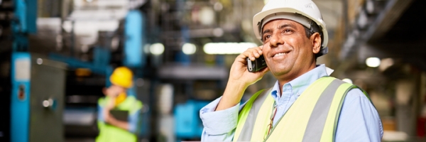 employee with hard hat on cell phone in commercial building